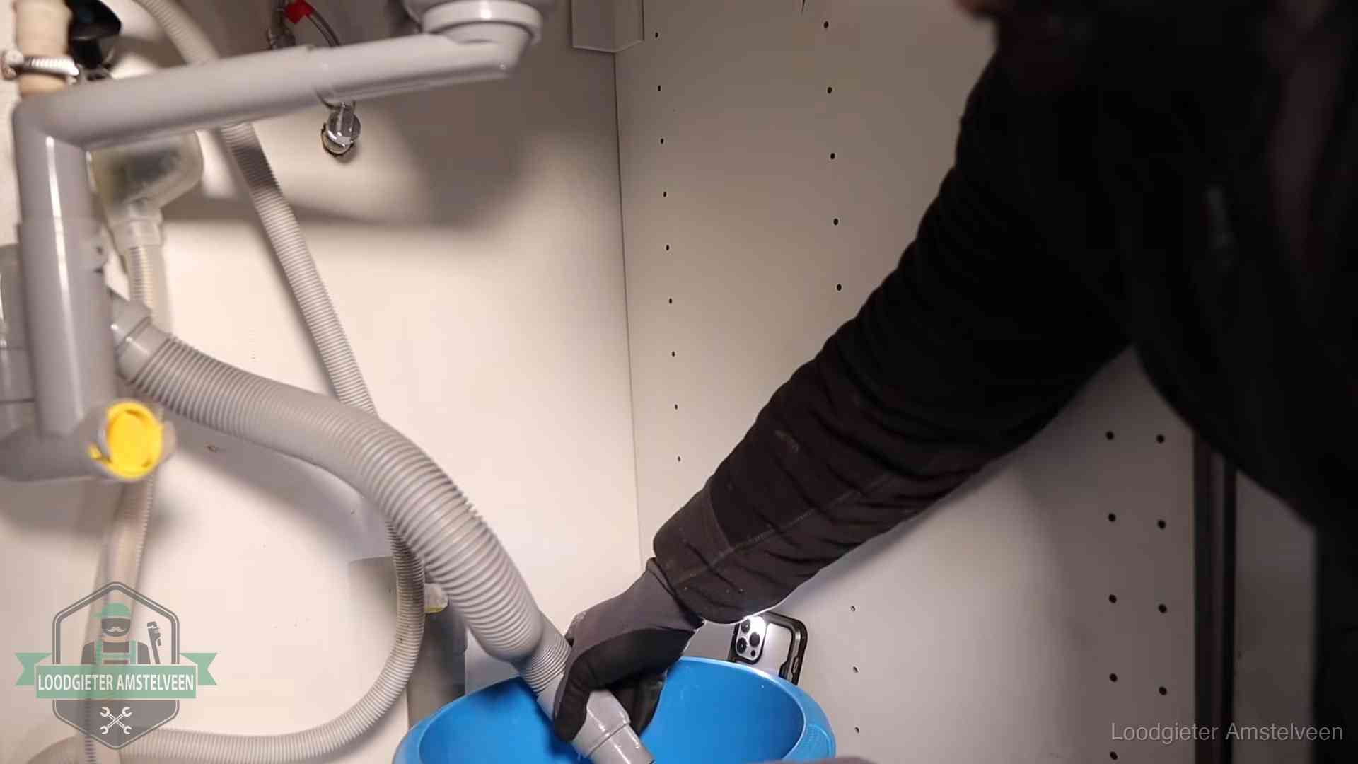 Afvoerslang loopt leeg in een emmer onder de gootsteen in Amstelveen, een klus die je zelf kunt doen