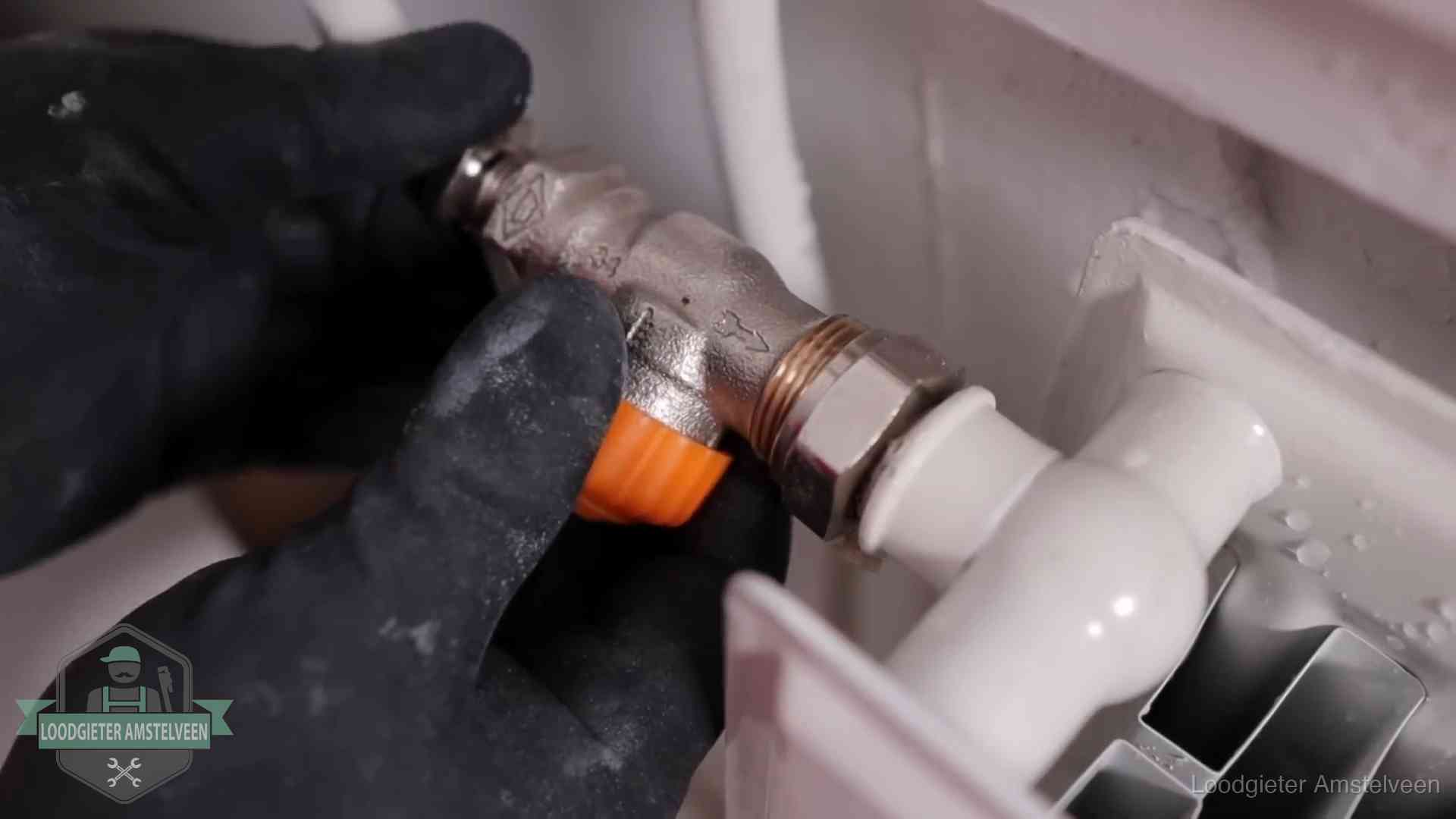 Thermostaatkraan wordt gemonteerd op een radiator in Amstelveen voor het stookseizoen