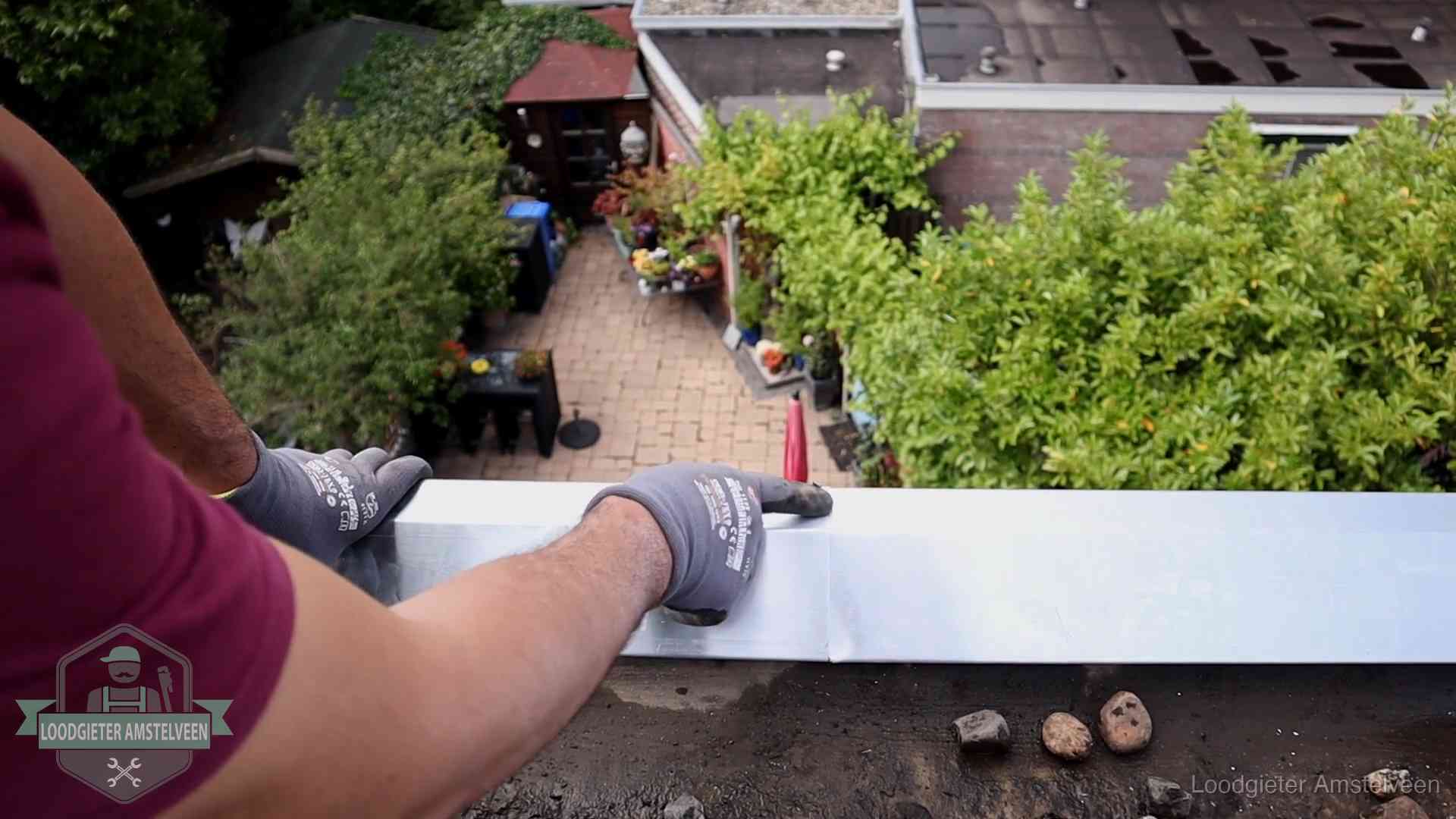 Vakman plaatst een daktrim op de dakrand van een woning in Amstelveen