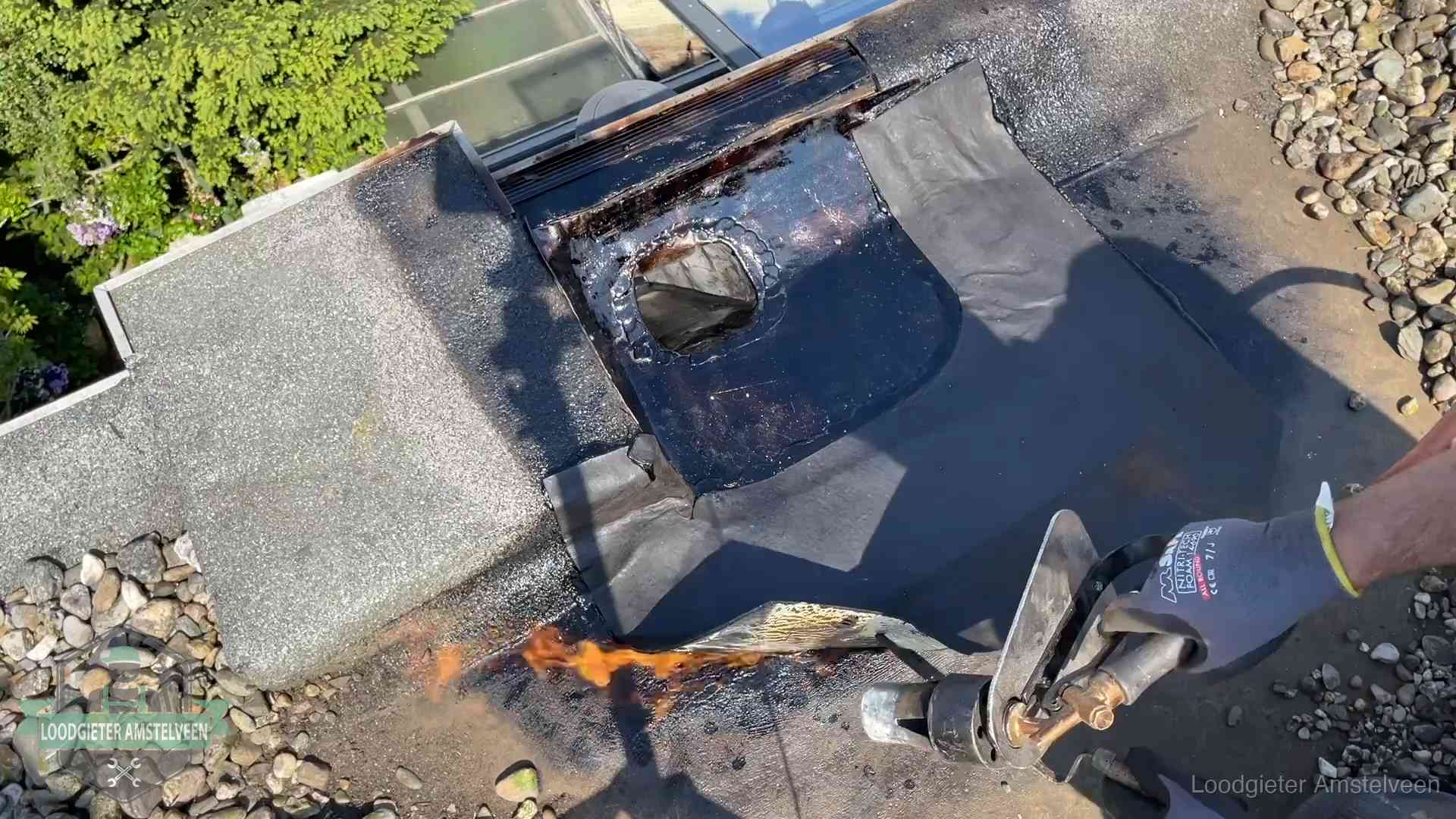 Dakdekker brandt bitumen rond een doorvoer tijdens een daklekkage-reparatie in Amstelveen