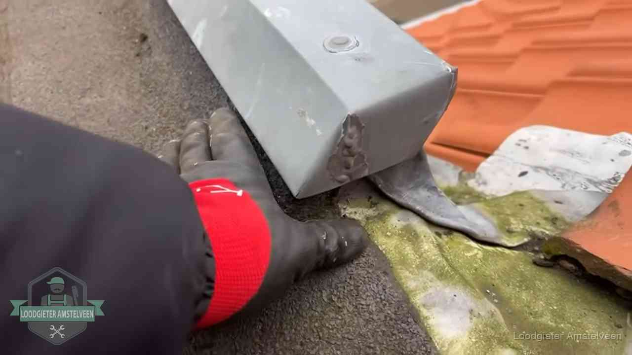 Controle van een zinken hemelwaterafvoer met loodslab bij dakpannen in Amstelveen