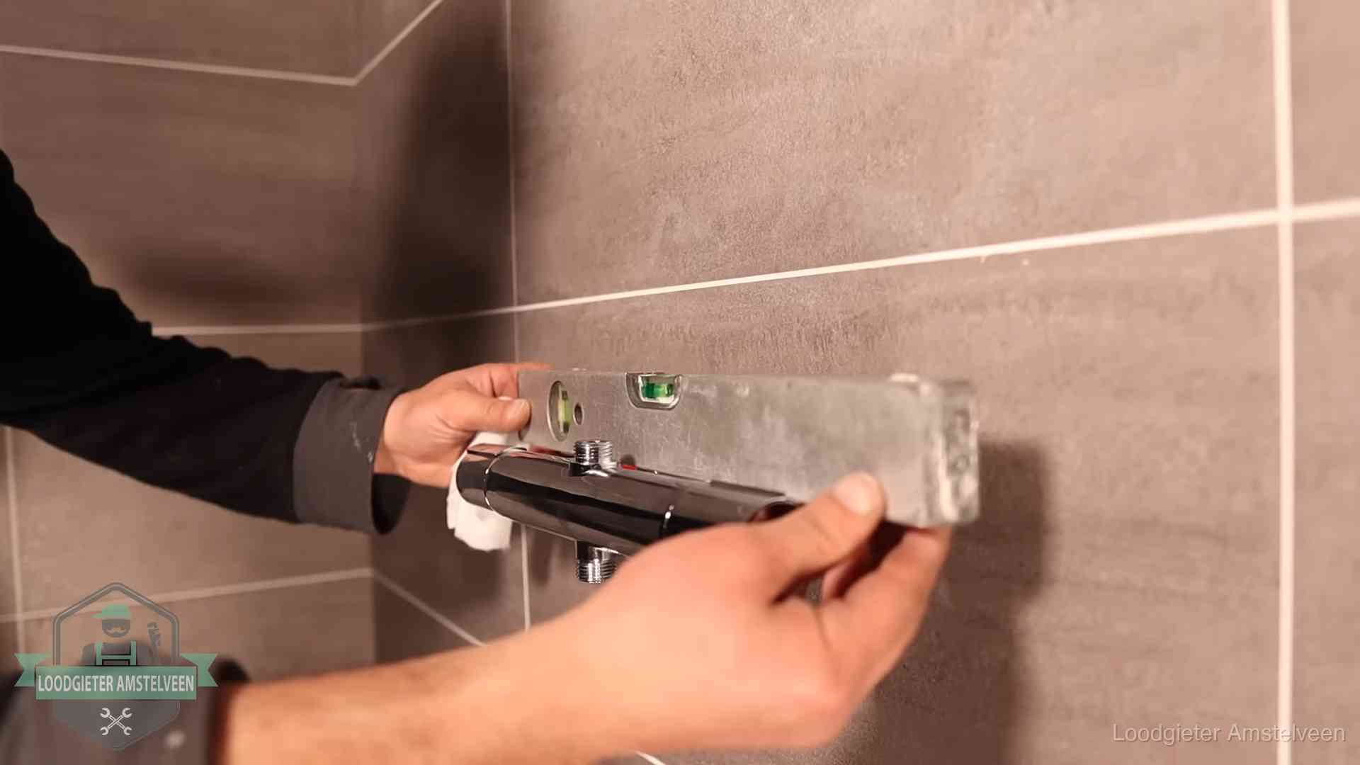 Loodgietersbedrijf voor sanitair in Amstelveen Loodgieter lijnt een douchekraan uit met een waterpas in een woning in Amstelveen