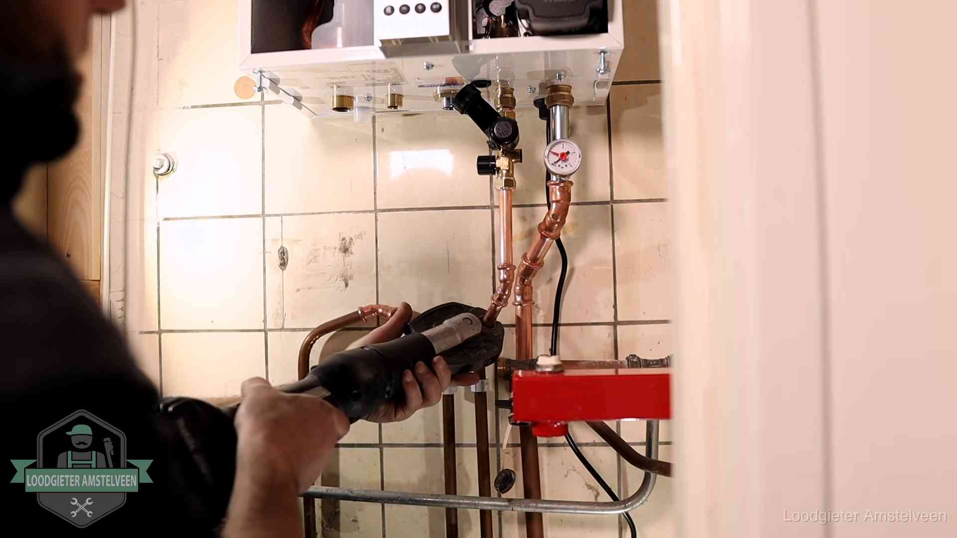 Monteur werkt aan de leidingen onder een cv-ketel in Amstelveen