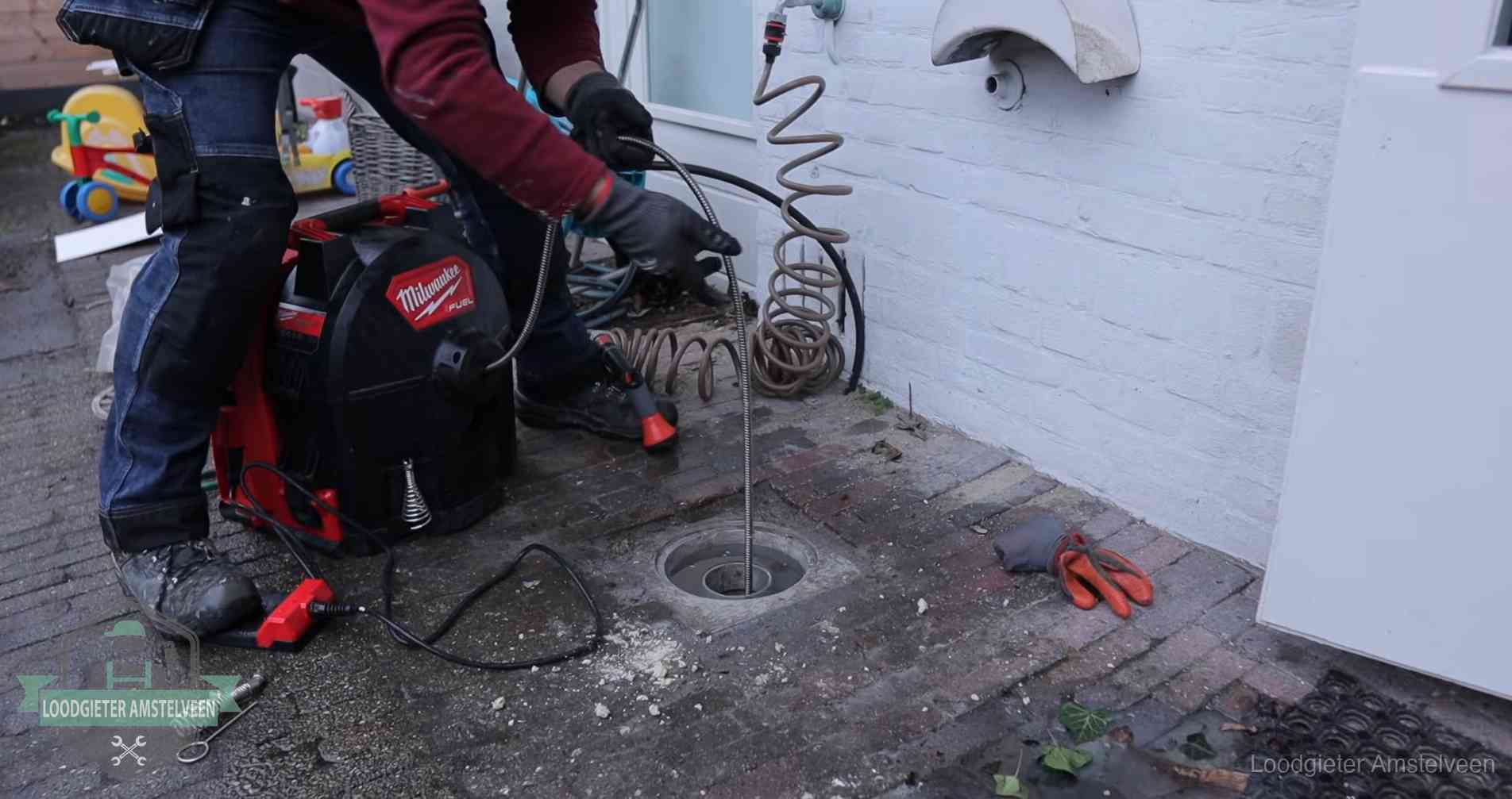 Ontstoppingsputje in de bestrating naast de gevel van een woning in Amstelveen