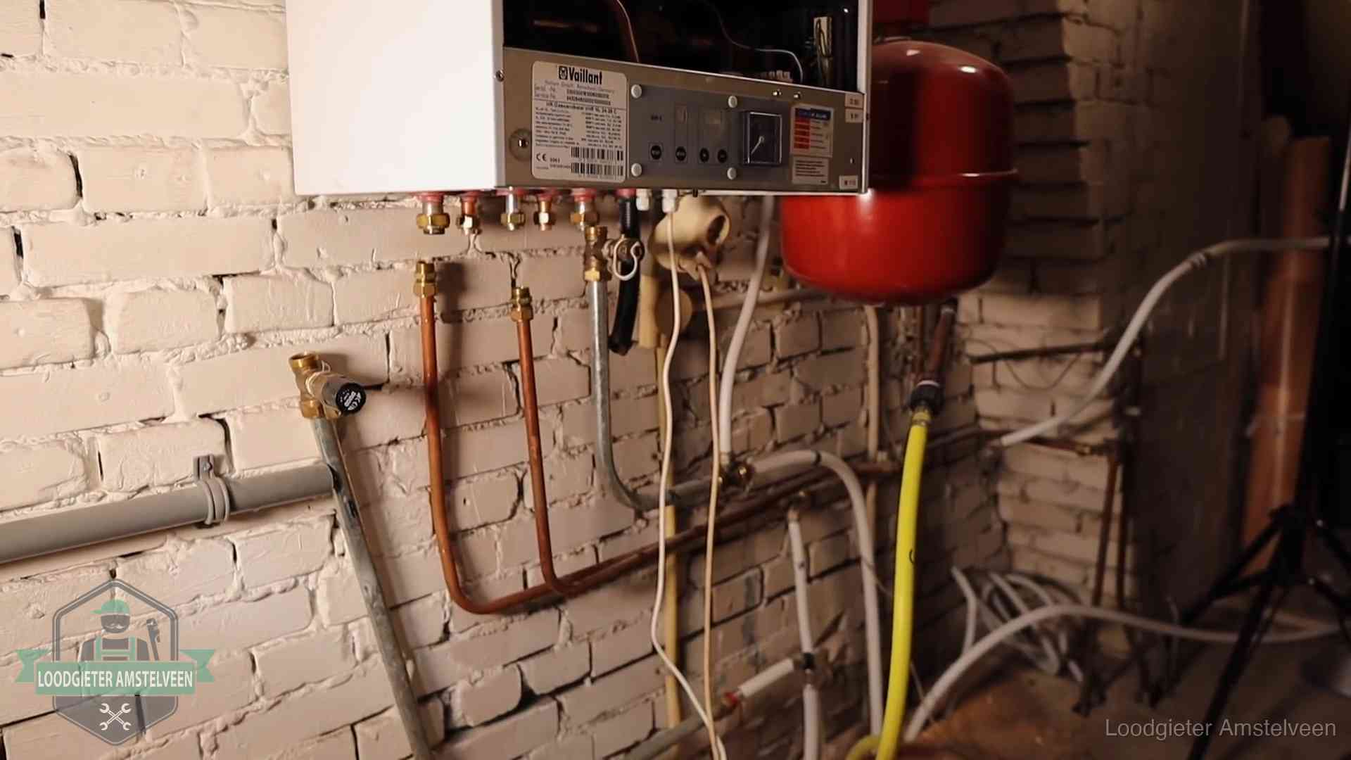 Verouderde cv-ketel met een wirwar van oude leidingen in een woning in Amstelveen