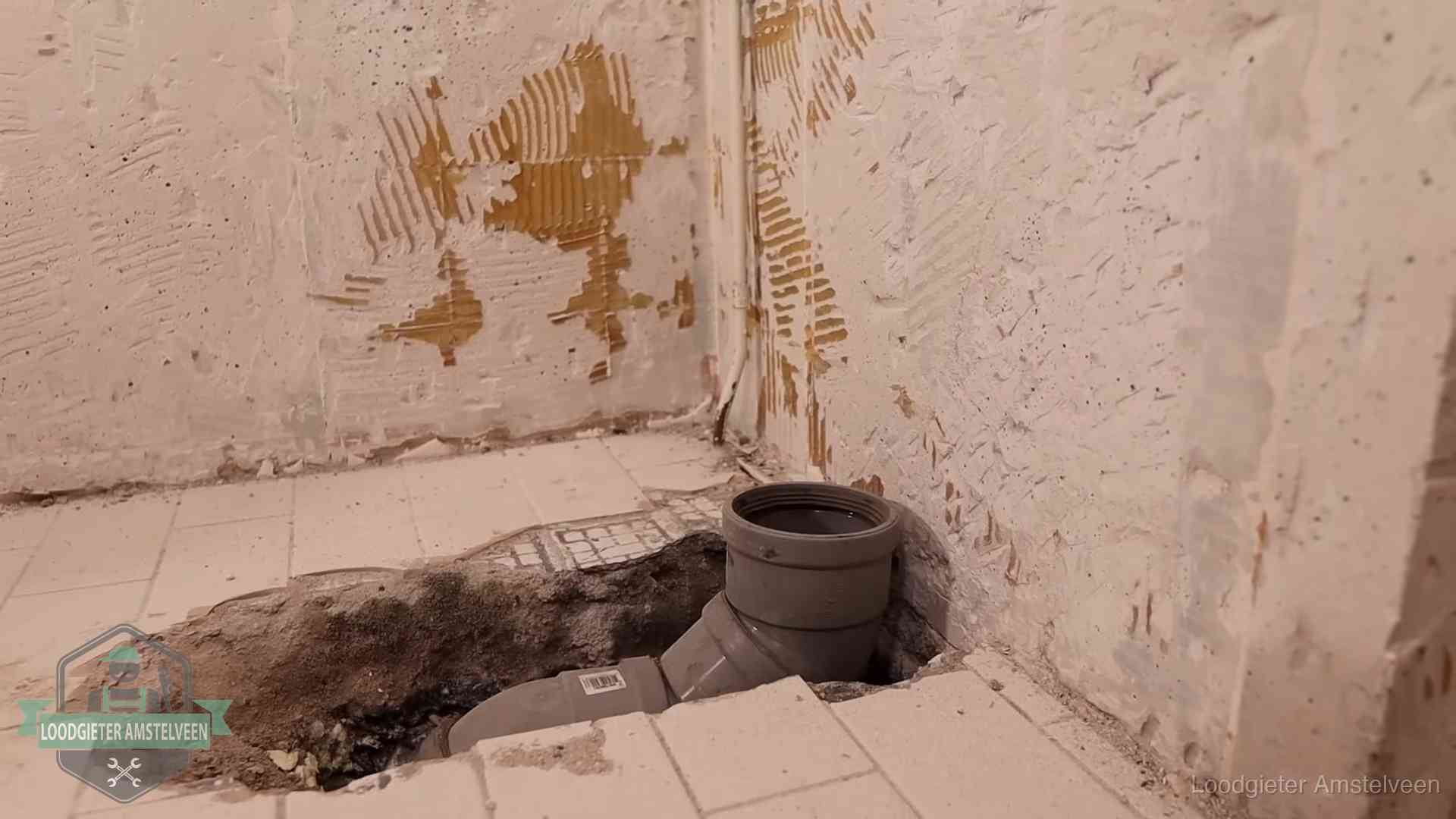 Opengebroken vloer met een nieuwe pvc-rioolbocht in een gegraven sleuf in Amstelveen