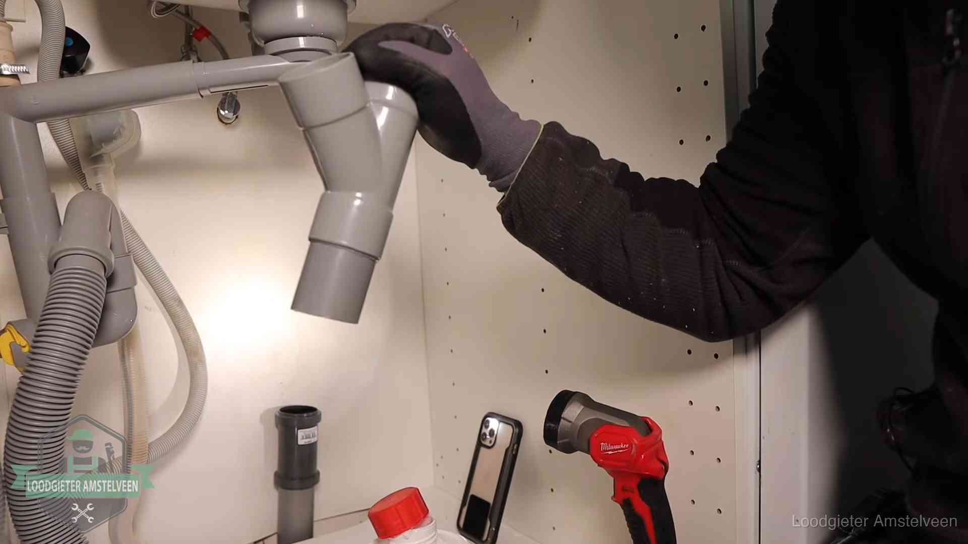 Loodgieter demonteert het sifon- en afvoerwerk onder een gootsteen in Amstelveen bij stankklachten