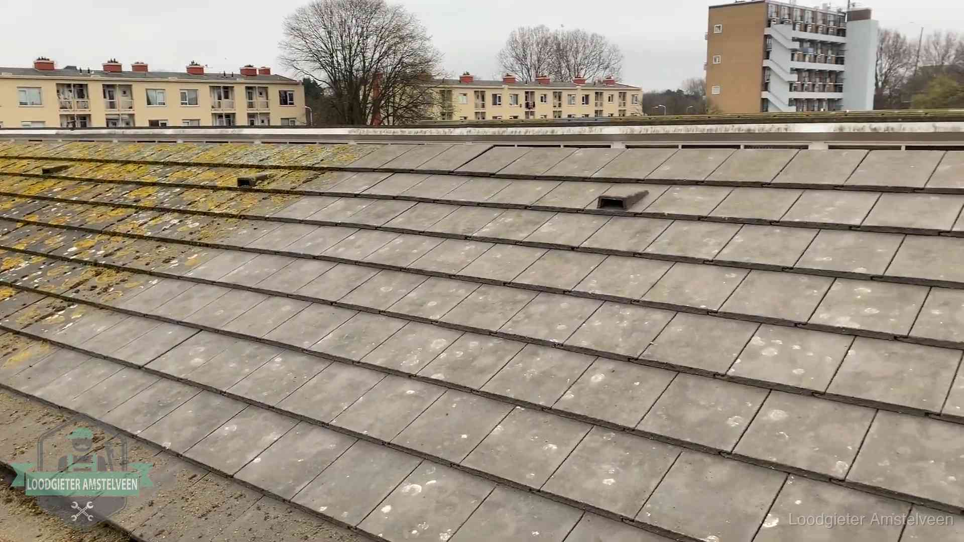 Schuin dak met betonpannen vol mos in Amstelveen, een risico op lekkage bij de pannen