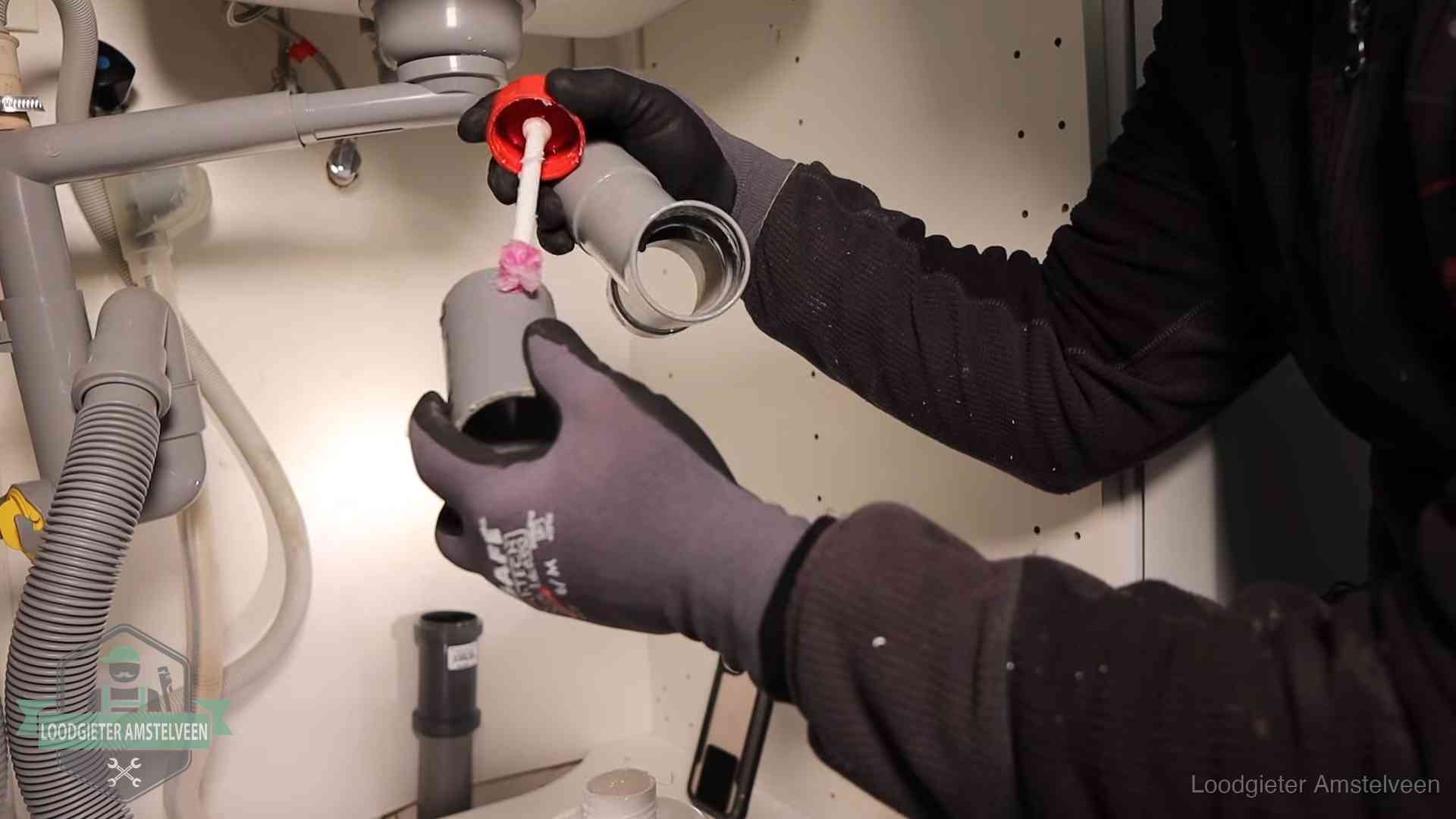 Loodgieter demonteert en reinigt de sifon onder een keukenkast in Amstelveen