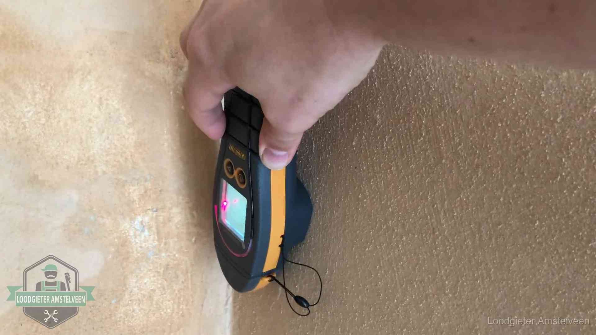 Vochtmeter tegen een muur met vochtplekken tijdens het opsporen van een daklekkage in Amstelveen